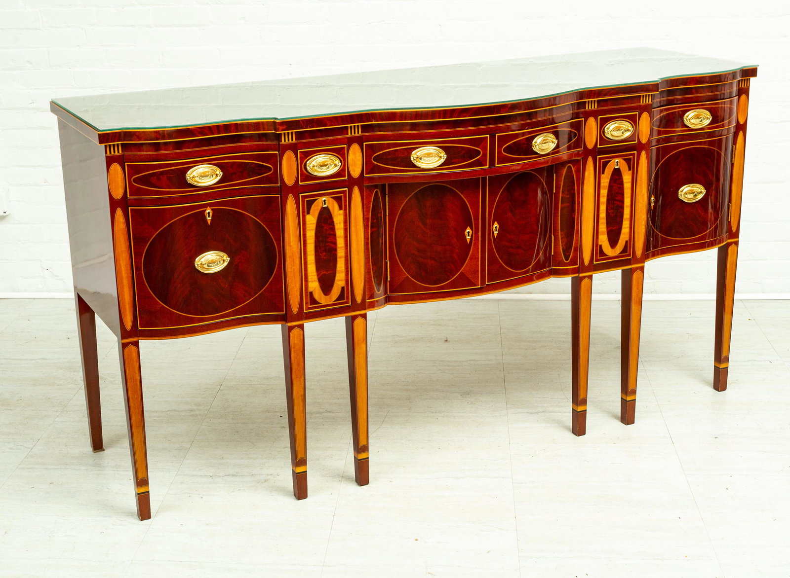 HEPPLEWHITE STYLE CARVED MAHOGANY SIDE BOARD H 3'4" L: HEPPLEWHITE STYLE CARVED MAHOGANY SIDE BOARD H 3'4" L 6'4" D 2'3" With brass handles. Having eight tapered legs.