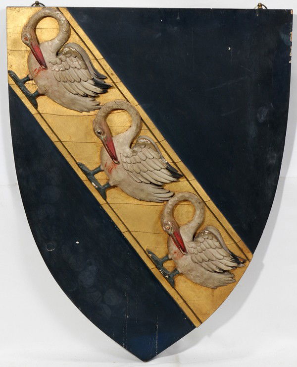 ANTIQUE CARVED/POLYCHROME PINE HERALDIC SHIELD: ANTIQUE CARVED & POLYCHROME PINE HERALDIC SHIELD, C. 1900, 25" X 19":Having a rich, deep blue ground on which a carved gold band is decorated with carved images of three pelicans, shown pecking their