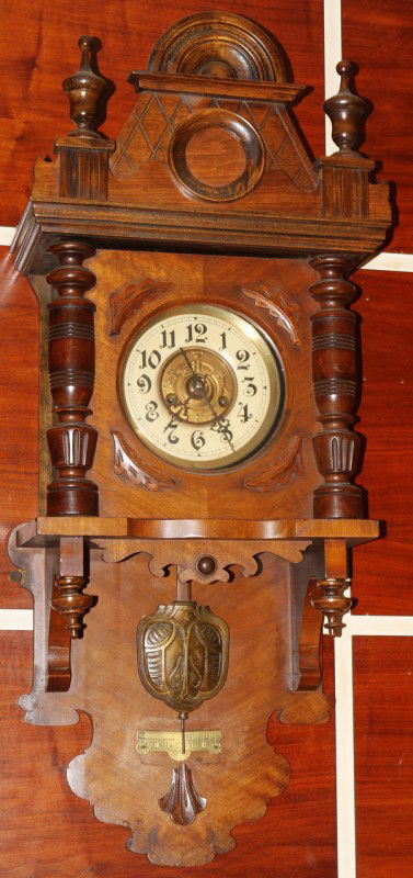 VICTORIAN STYLE WALNUT HANGING CLOCK, H 36",: VICTORIAN STYLE WALNUT HANGING CLOCK, H 36", W 14":Flanked by half-columns, glass panel door, pendulum, two-key wind. From the collection of Joseph and Norina Simon, Grosse Pointe Farms, Mi.