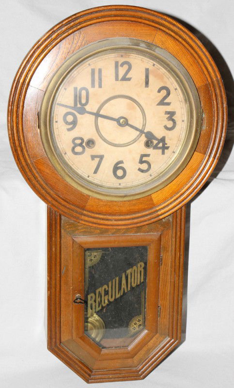 OAK REGULATOR WALL CLOCK, CA. 1900, H 21" W 12": OAK REGULATOR WALL CLOCK, CA. 1900, H 21", W 12":With key, fancy brass pendulum.