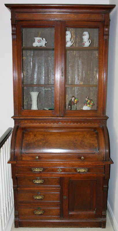EASTLAKE WALNUT SECRETARY, CYLINDER ROLL TOP: EASTLAKE WALNUT SECRETARY, CYLINDER ROLL TOP, CIRCA 1880, H 89":measuring: 89" H. x 42" W. x 25" D. having a crown molding at the cornice, framed glass doors opening to two shelves; a roll top opens t