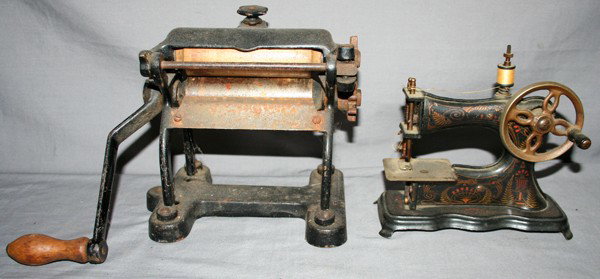 CHILD'S TOY SEWING MACHINE & CLOTHES WRINGER, : CHILD'S TOY SEWING MACHINE & CLOTHES WRINGER, C1930, 2 PCS., W 7" & 12", H 7" & 8":both are hand operated with stamped metal sewing machine painted black with stenciled designs and gilt metal flywheel