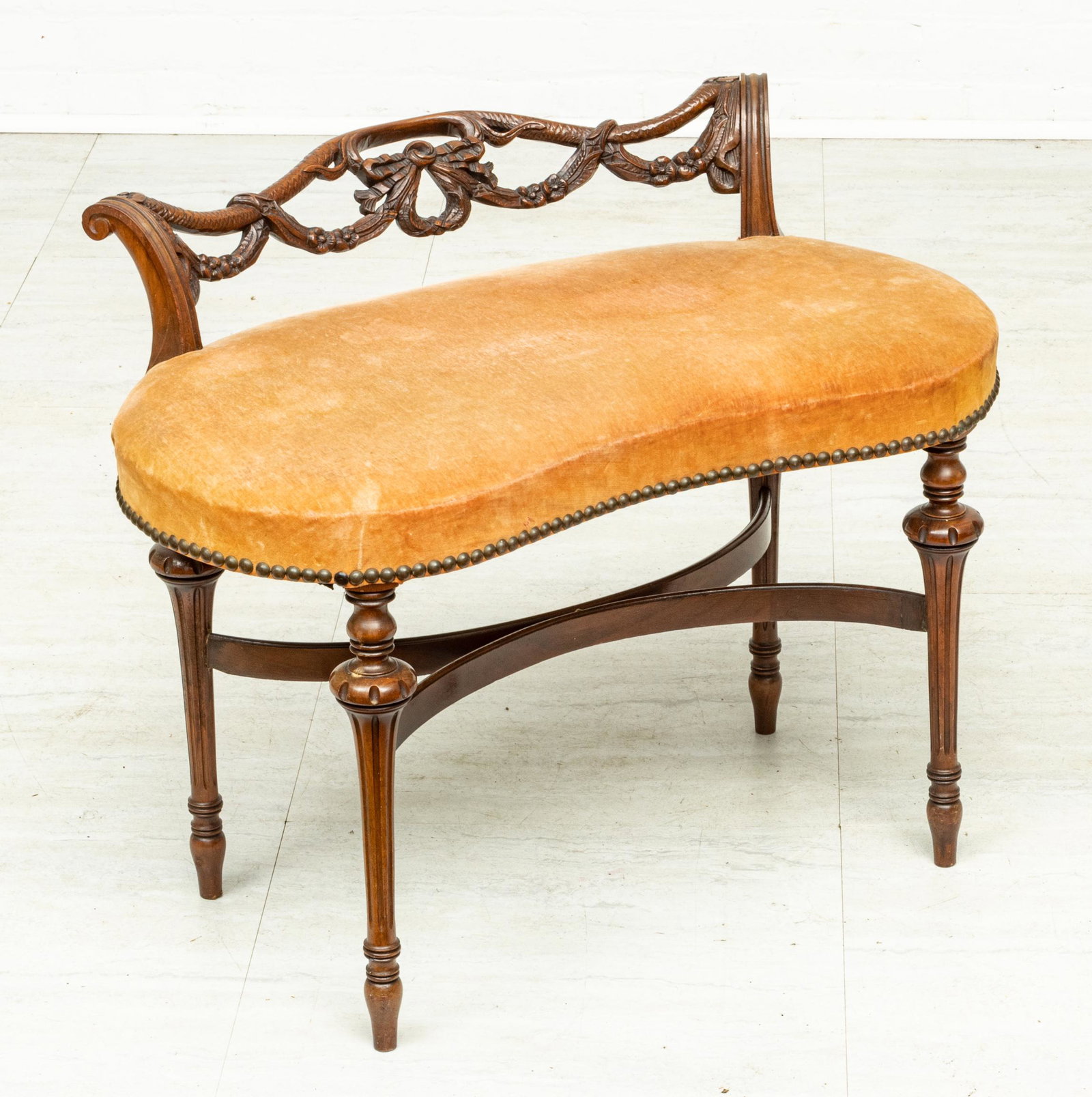 FRENCH STYLE CARVED WALNUT KIDNEY SHAPED BENCH CIRCA 1920 H 22" W 29" DIA 16": FRENCH STYLE CARVED WALNUT KIDNEY SHAPED BENCH CIRCA 1920 H 22" W 29" DIA 16" Bench having hand carved garland and swags. Tapered fluted legs in Louis XVI style. Circa 1920. Upholstered spring seat. P