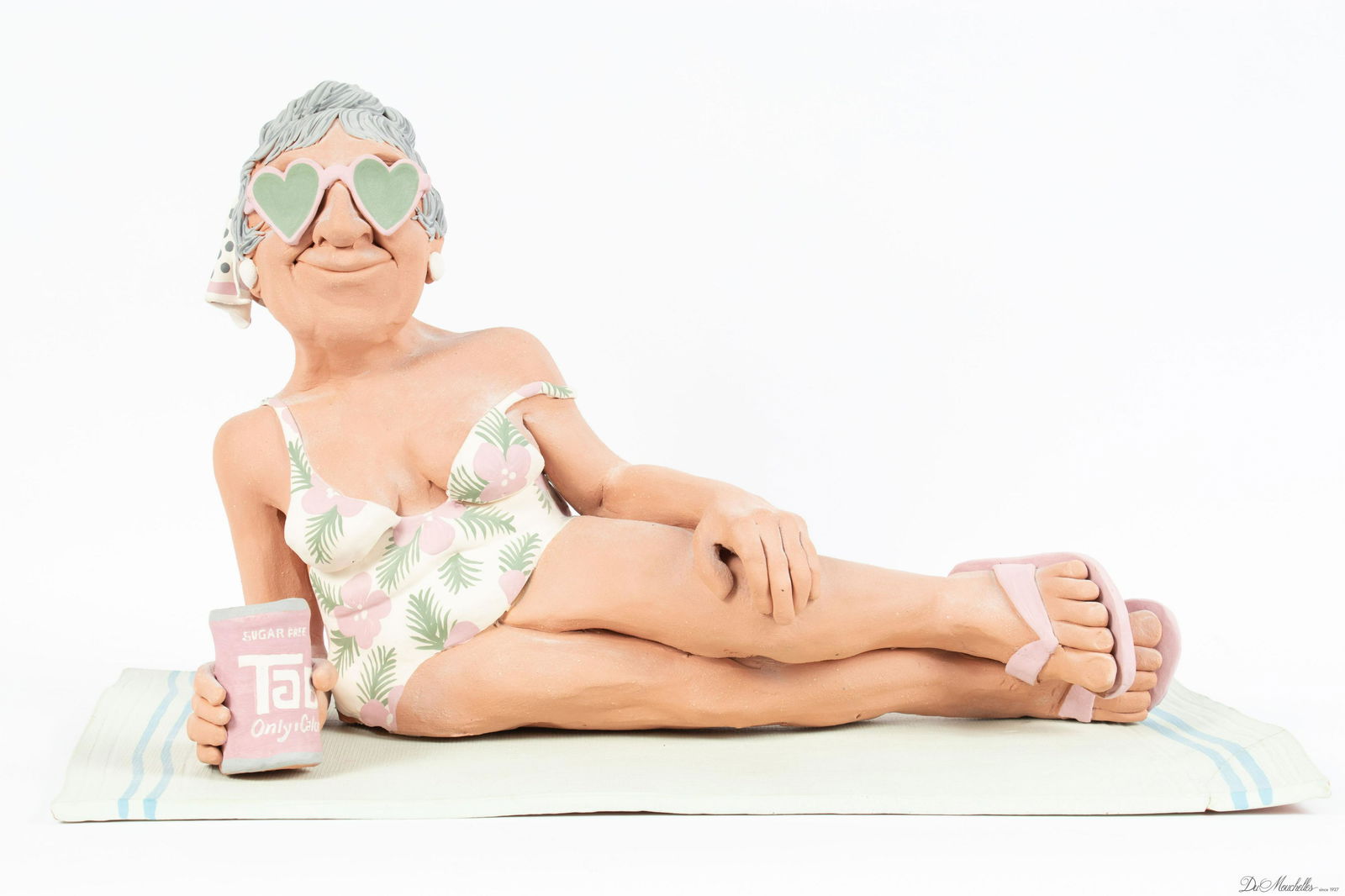 JOHN DAVIS STUDIOS TERRACOTTA SCULPTURE, 1987, H 11", W 19", D 9.75": JOHN DAVIS STUDIOS TERRACOTTA SCULPTURE, 1987, H 11", W 19", D 9.75" Terracotta sculpture depicting a woman reclining on a beach towel with a can of Tab. Signed J. Davis 87 on the back of the woman's