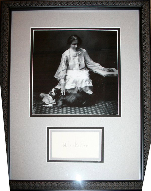 HELEN KELLER SIGNED CARD WITH BLACK/WHITE PHOTO: HELEN KELLER SIGNED CARD WITH BLACK & WHITE PHOTO, H 13", W 8":photo depicts Keller with her pet dog. framed and matted under glass. Cut autograph floated with clear corner mounts below photo.