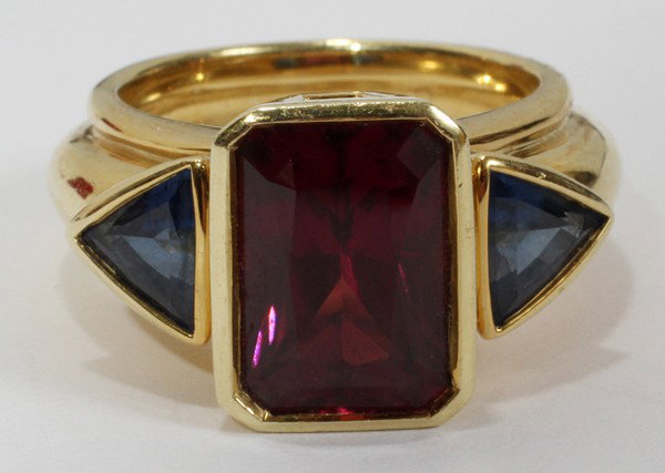 18KT YELLOW GOLD RING W/GARNET & 2 SAPPHIRES, : 18KT YELLOW GOLD RING WITH 5.75 CT. RHODOLITE GARNET & 2 SAPPHIRES, DESIGNED BY RUTH TAUBMAN:Sapphires 1.84 ct., trillion cut. Designed by Ruth Taubman of Ann Arbor. From the Collection of Bruce and D