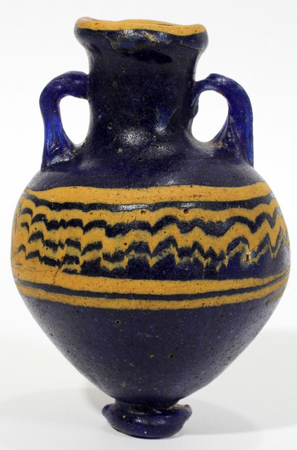 EASTERN MEDITERRANEAN STYLE GLASS VESSEL, H 3": EASTERN MEDITERRANEAN STYLE GLASS VESSEL, H 3":Core formed glass style amphora vessel, a cobalt blue ovoid body with cylindrical neck and everted rim flanked by twisted handles, golden yellow bands an