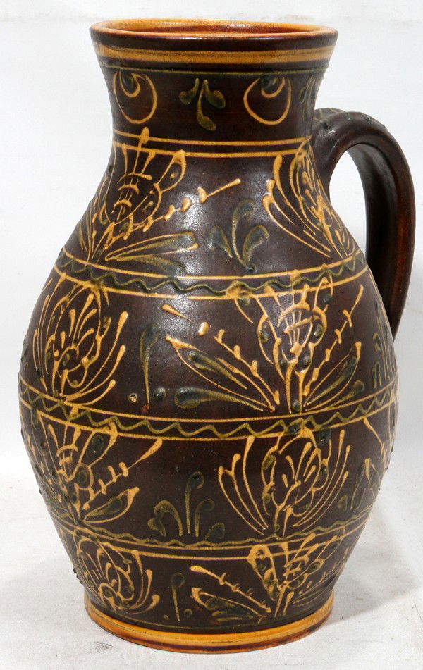 AMERICAN REDWARE POTTERY PITCHER, 1965, H 12": AMERICAN REDWARE POTTERY PITCHER, 1965, H 12":A bluster-form pitcher with yellow and green slip decoration on a matte brown ground, dated 1965 vertically to the right of the handle; an impressed maker