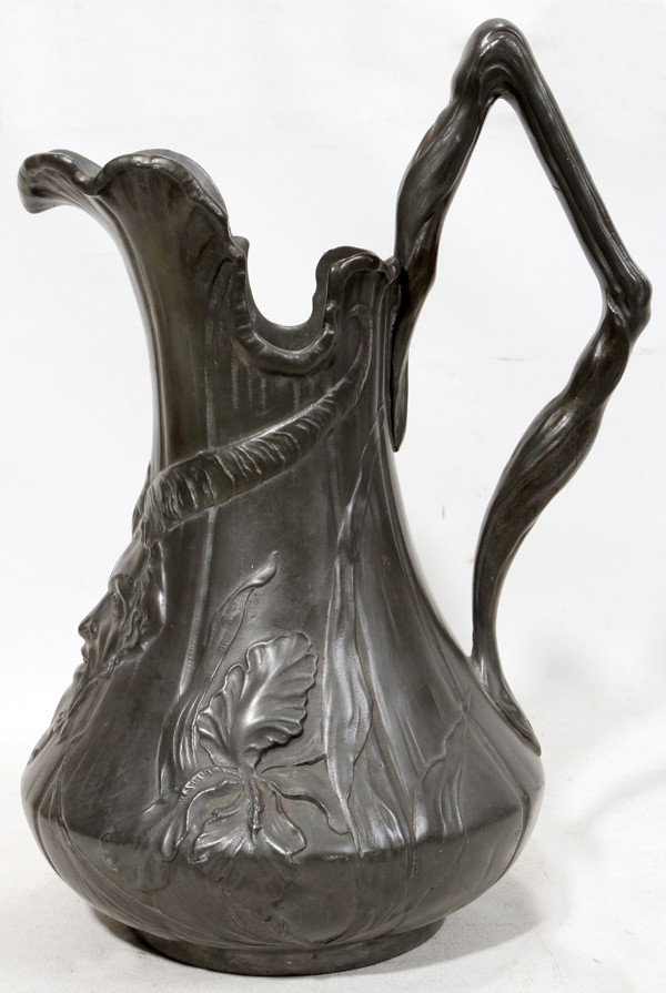 KAYSERZINN PEWTER MASK PITCHER, C. 1910, H 13": KAYSERZINN PEWTER MASK PITCHER, C. 1910, H 13":An art nouveau pewter pitcher with Bacchic mask below the spout and iris motif; stamped at the underside "7/Kayserzinn/4061/P". Measures H.12 3/4".
