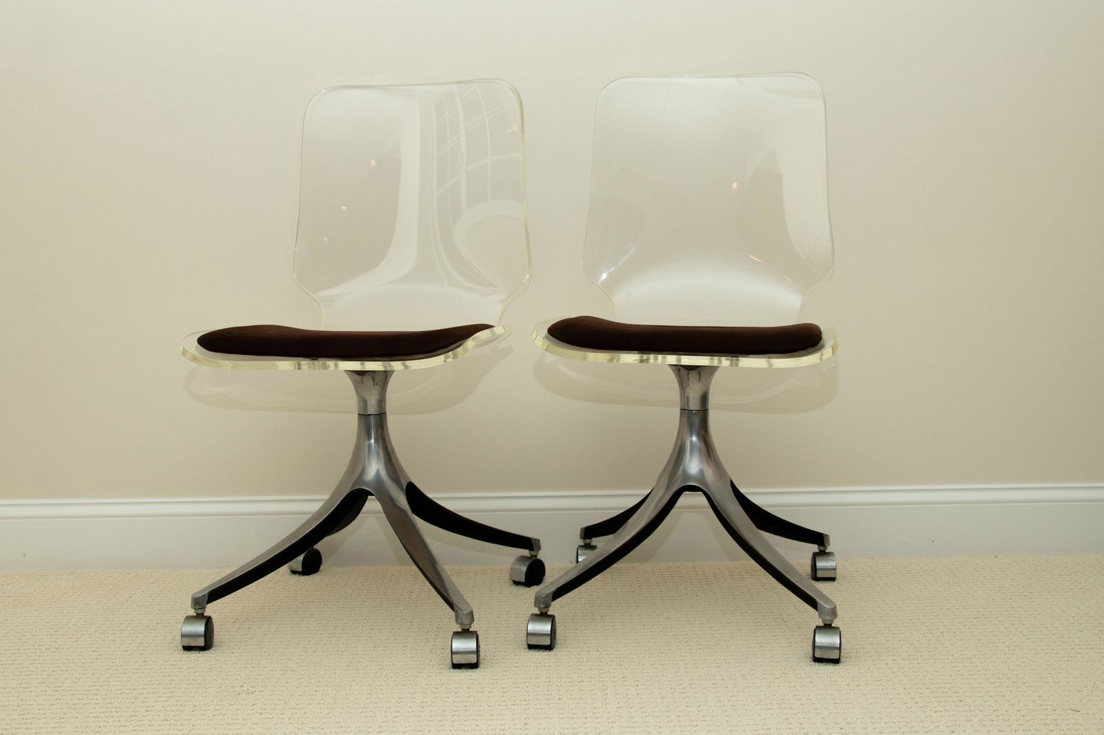 HILL MANUFACTURING CORPORATION LUCITE AND STEEL SWIVEL CHAIRS, C. 1978, PAIR, H 34", DIA 24" (BASE): HILL MANUFACTURING CORPORATION LUCITE AND STEEL SWIVEL CHAIRS, C. 1978, PAIR, H 34", DIA 24" (BASE) Having steel pedestal bases with rollers. Clear lucite bodies with brown ultrasuede seat cushions. M
