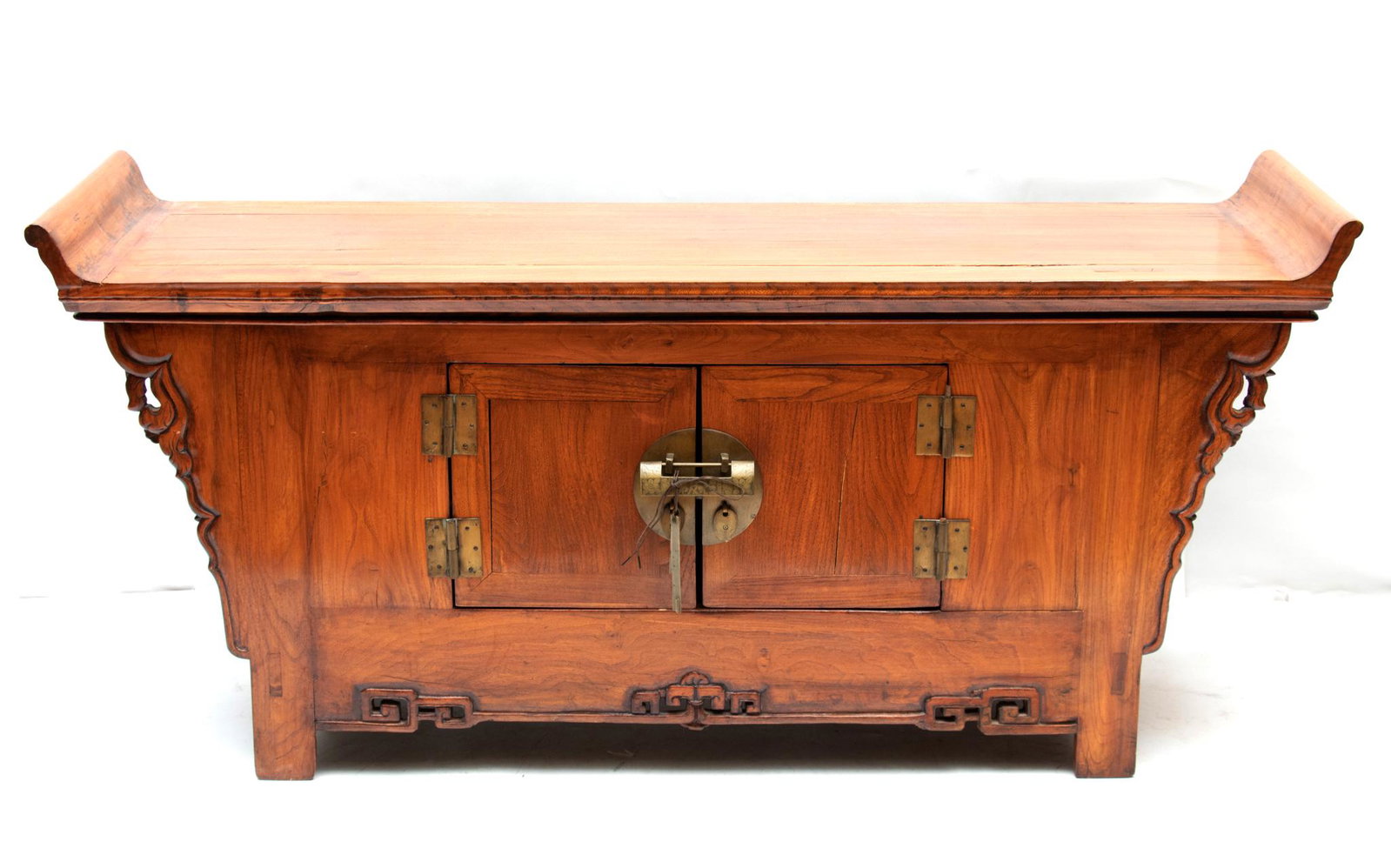 CHINESE CARVED WOOD CABINET, H 25 1/2", L 55 1/4", D 15 1/4": CHINESE CARVED WOOD CABINET, H 25 1/2", L 55 1/4", D 15 1/4" Scrolled top at the ends, above a carved sides, centered by two wood paneled doors with brass hardware and lock. Carved and pierced lower a