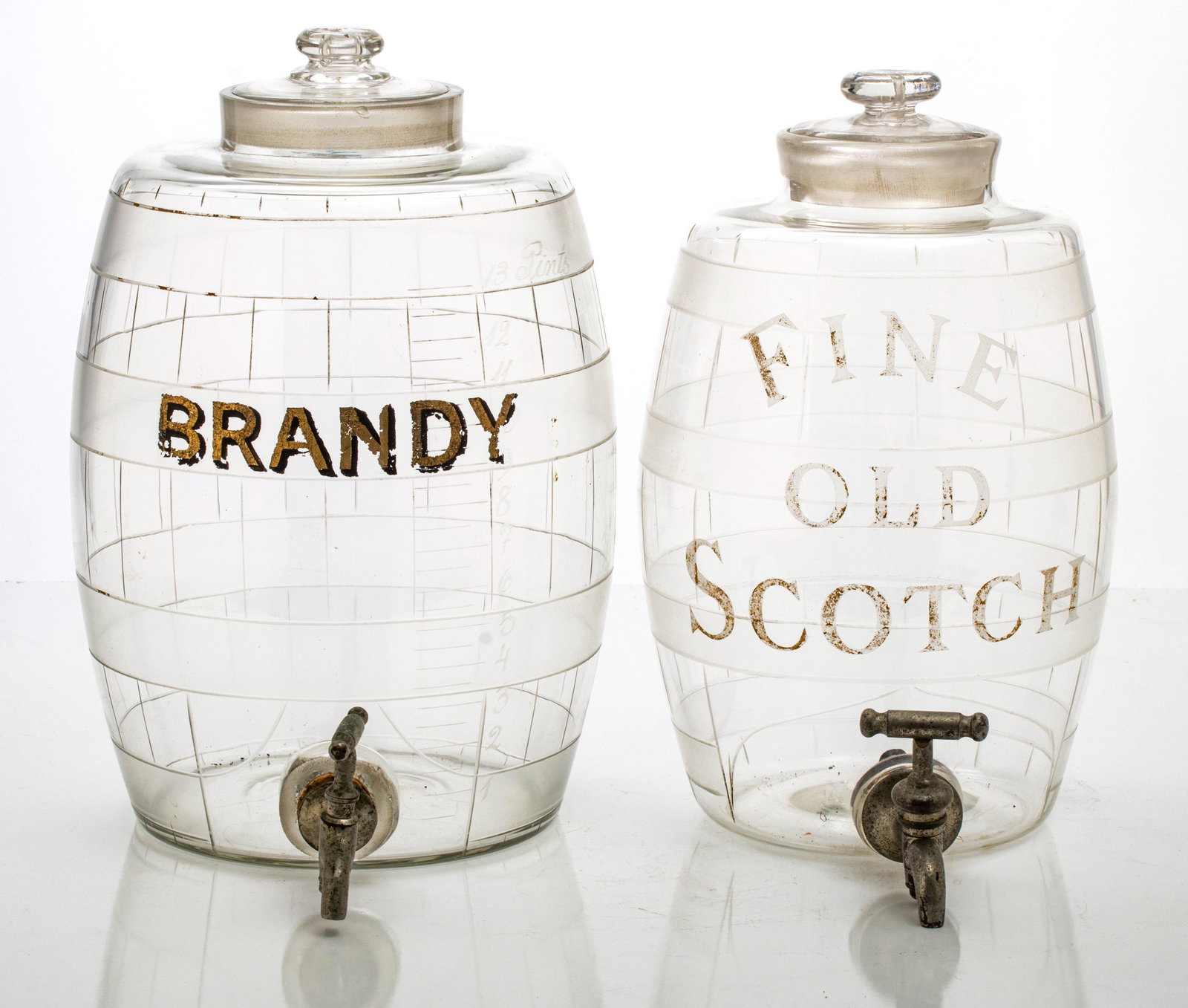 GLASS BAR COUNTER TOP BRANDY & SCOTCH BARRELS, 19H.C. TWO H 12", 13": GLASS BAR COUNTER TOP BRANDY & SCOTCH BARRELS, 19H.C. TWO H 12", 13" Stenciled "Fine Old Scotch" and "Brandy". Pewter spigots. Glass covers to containers.