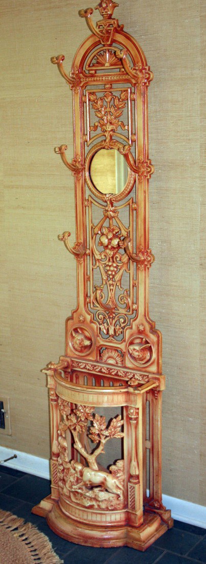 METAL HALL TREE, 20TH C, H 76", W 18": METAL HALL TREE, 20TH C, H 76", W 18":pierced design with leaf and floral designs and having seven coat hooks on tall narrow frame with round mirror in the center; umbrella stand at the bottom having 