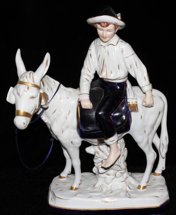 ROYAL DUX FIGURE OF A BOY ON A DONKEY, H 15", : ROYAL DUX FIGURE OF A BOY ON A DONKEY, H 15", W 12":A porcelain figure of a boy seated on a donkey, white with cobalt blue and fired gold decoration. .