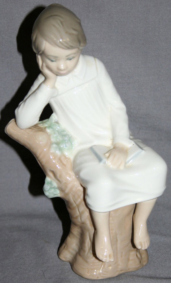 LLADRO PORCELAIN FIGURE, H 8": LLADRO PORCELAIN FIGURE, H 8":Boy in night clothes sitting on a stump, reading a book, 8 1/2" H. Does not include box.