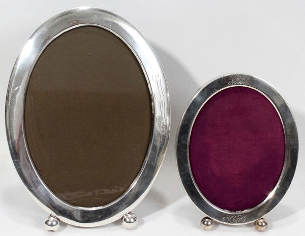 AMERICAN STERLING PHOTO FRAMES, EARLY 20TH C.: AMERICAN STERLING PHOTO FRAMES, EARLY 20TH C., TWO, H 7" & 10":Each sterling silver frame is oval in shape on two ball feet, with an engraved monogram, and having an easel back; measuring H.7" x 5 1/2