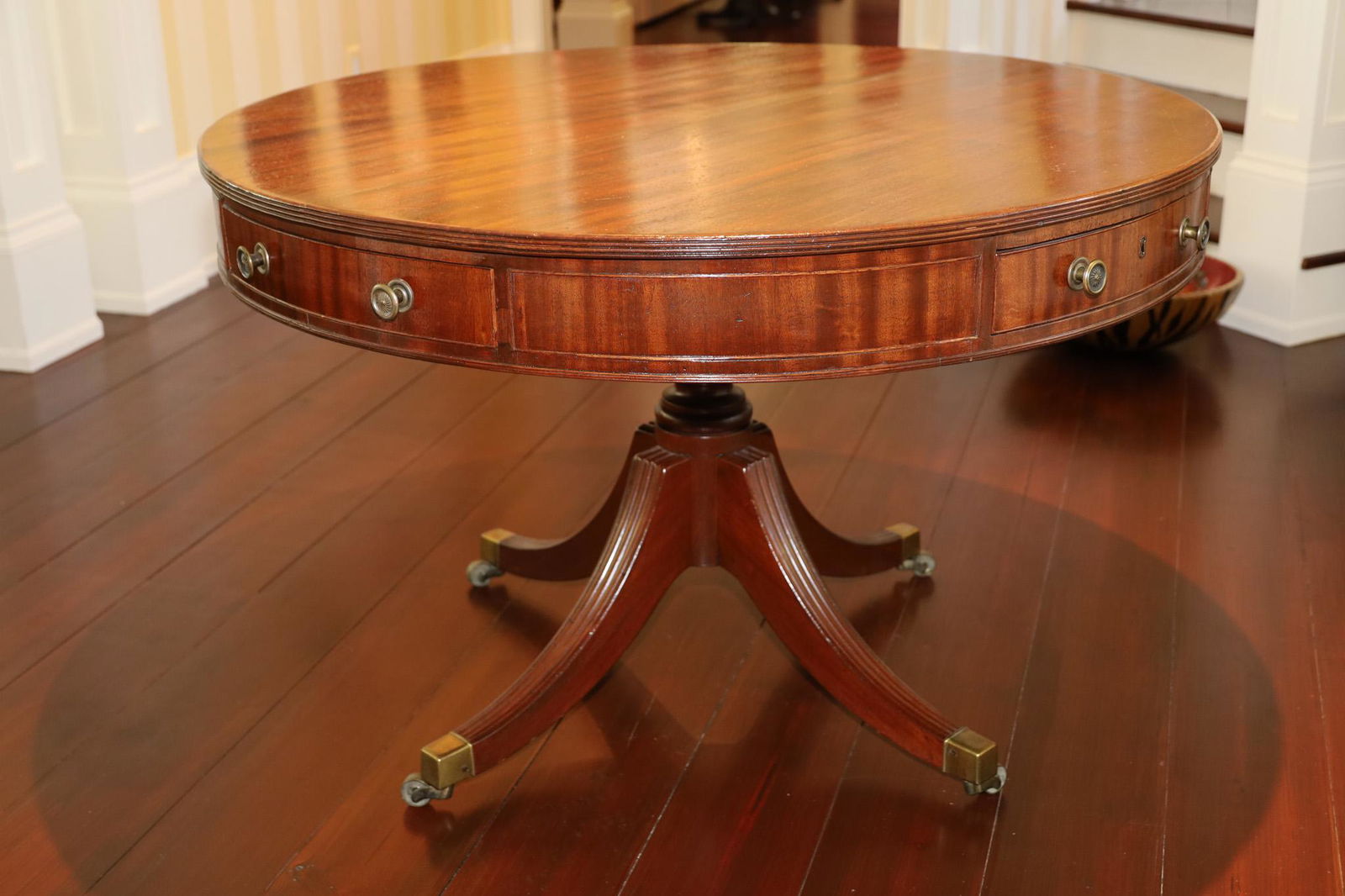 GEORGIAN STYLE MAHOGANY ROUND DRUM TABLE, CIRCA 1920 H 30", DIA 46": GEORGIAN STYLE MAHOGANY ROUND DRUM TABLE, CIRCA 1920 H 30", DIA 46" Having four drawers, Duncan Phyfe style, brass handles. On four legs with brass tip feet and casters. Quality fine furniture.From a