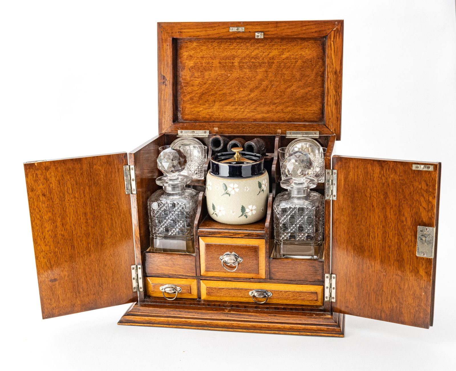English Tantalus and Smoking Set in Oak Case C 1880 H 13” W 14” D 10”: ENGLISH TANTALUS AND SMOKING SET IN OAK CASE C 1880 H 13" W 14" D 10" Cabinet with two front hinged doors (key included) and a hinged upper panel. Encases pair of square hand cut whiskey bottles and 4