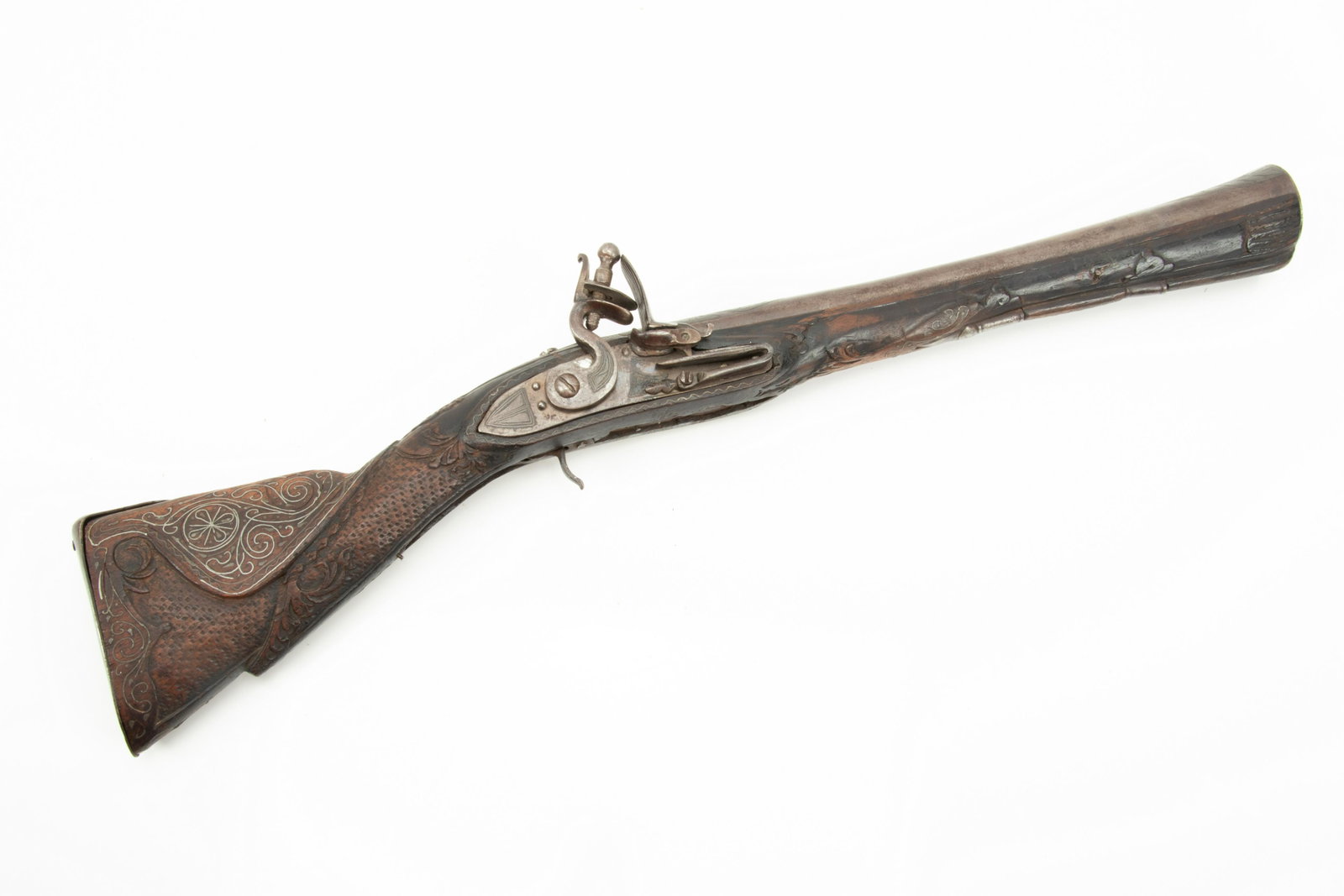 European Flintlock Blunderbuss, Early 19th C., L 21.25” Overall: EUROPEAN FLINTLOCK BLUNDERBUSS, EARLY 19TH C., L 21.25" OVERALL Intricately carved walnut stock with silver wire inlay. Lockplate, hammer and the top of the barrel also have silver overlay designs. No