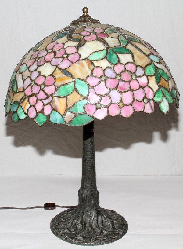 AMERICAN LEADED SLAG GLASS & METAL TABLE LAMP: AMERICAN LEADED SLAG GLASS & PATINATED METAL TABLE LAMP, EARLY 20TH CENTURY, H 23 1/2", DIA 18":Beautifully leaded glass shade with motifs of pink blossoms, green leaves and caramel accents rests atop