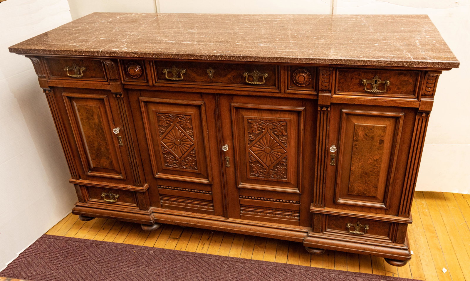 English Eastlake Marble Top Carved Walnut Buffet, H 38'' W 66'' Depth 25'': English Eastlake Marble Top Carved Walnut Buffet, H 38'' W 66'' Depth 25'' Rouge marble top. Three upper drawers, with twist brass drop handles, above four carved and burl walnut paneled doors. On six