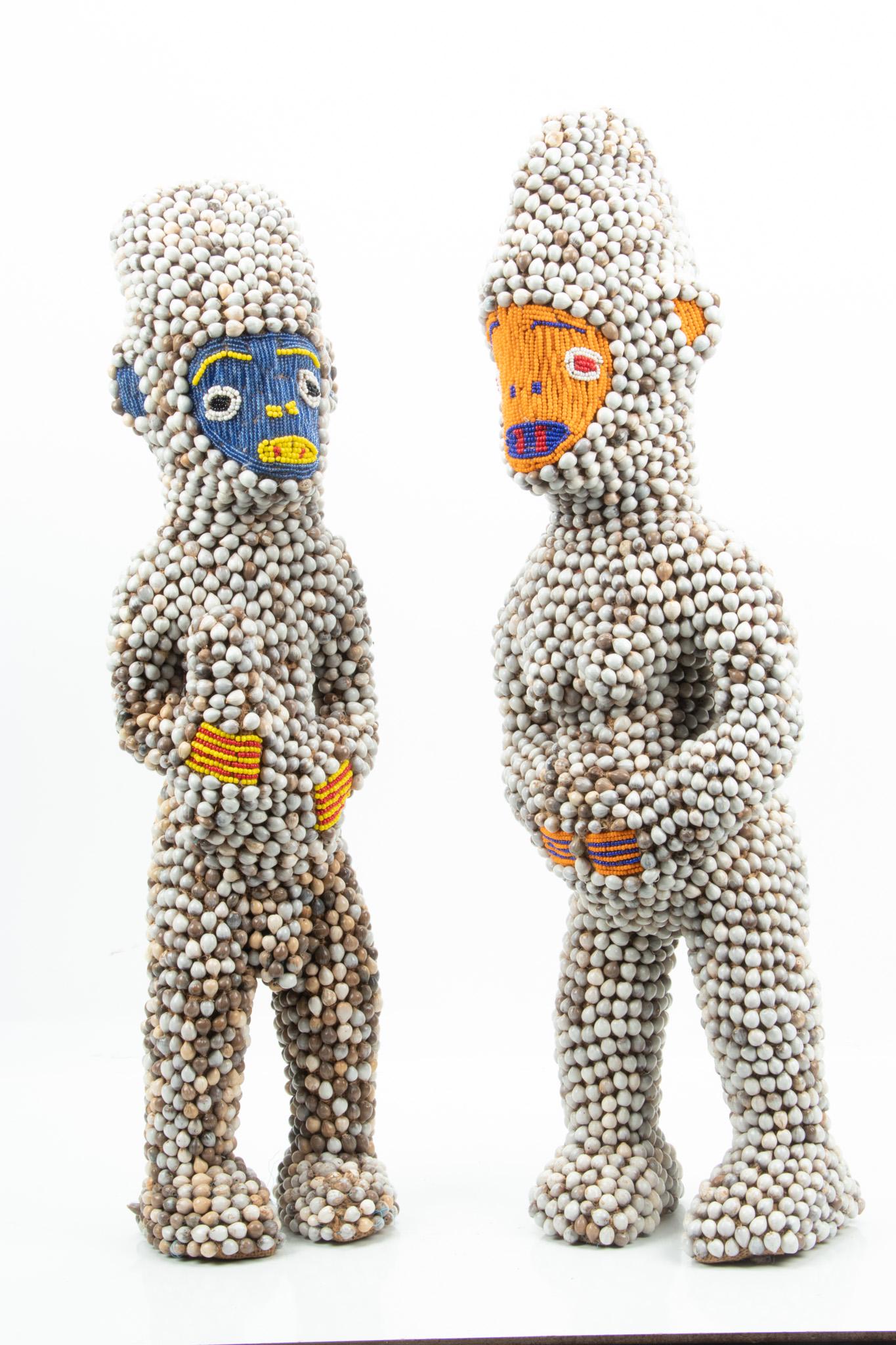 African, Yoruba, Nigeria, Bead And Shell Male And Female Figures With Orange And Blue Faces, H: African, Yoruba, Nigeria, Bead And Shell Male And Female Figures With Orange And Blue Faces, H 25.5", W 8" Private Collection, Bloomfield Township, Michigan.