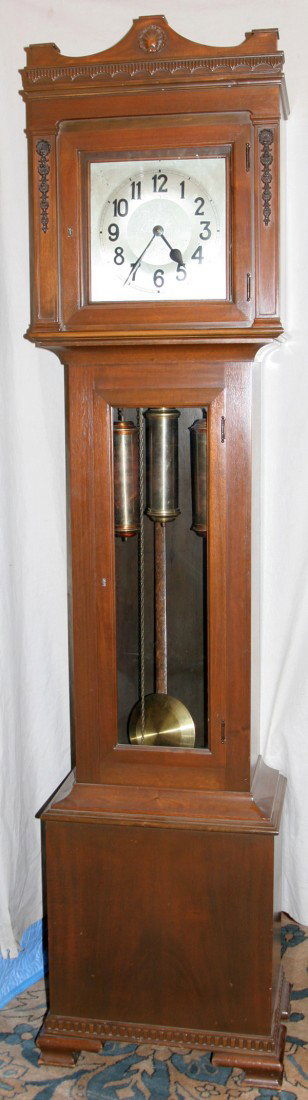 GERMAN MAHOGANY TALL CASE CLOCK, CIRCA 1920,: GERMAN MAHOGANY TALL CASE CLOCK, CIRCA 1920, H 84":carved crest above a glass access door at the face with Arabic numerals; second glass access door opening to three weights and a wood and brass pendu