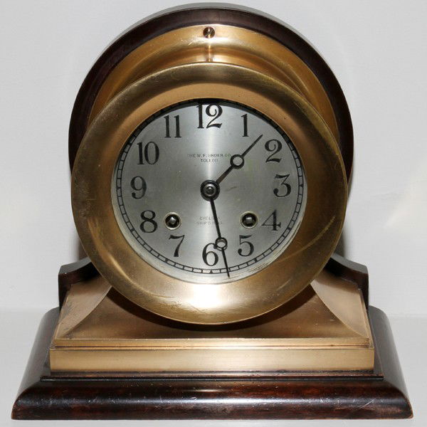 W.F. BROER CO. CHELSEA SHIP'S BELL MANTLE CLOCK: W.F. BROER CO. CHELSEA SHIP'S BELL BRASS & WOOD MANTLE CLOCK, H 8", L 8 1/2":With a brass case and wood base. Includes key.