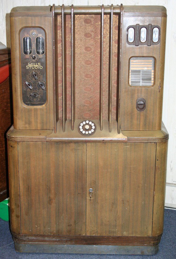 MILLS NOVELTY CO "STUDIO" JUKEBOX, WALNUT CASE: MILLS NOVELTY CO "STUDIO" JUKE BOX, WALNUT CASE, C1930'S, H 63", W 40", D 24":Art Deco style, having a walnut case with a panel on the left side with bass, treble, and balance controls; coin receptacl