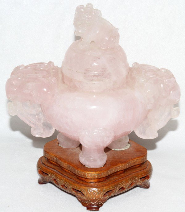 CHINESE ROSE QUARTZ COVERED URN, H 6", W 7": CHINESE ROSE QUARTZ COVERED URN, H 6", W 7":The domed cover centered by a foo dog finial, the urn raised on three feet and mounted to a teakwood base.