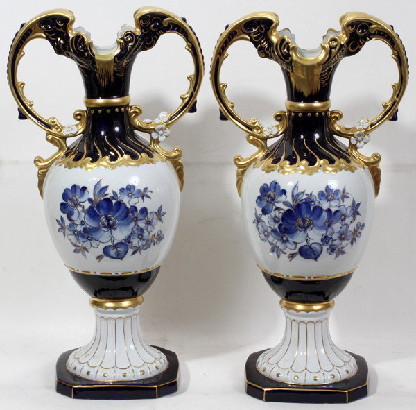 ROYAL DUX HAND-PAINTED PORCELAIN URNS, PAIR,: ROYAL DUX HAND-PAINTED PORCELAIN URNS, PAIR, H 25", W 13" TO THE HANDLES:Each has a white ground with hand painted blue floral motifs and cobalt and gilt accents. Both are marked on the underside with