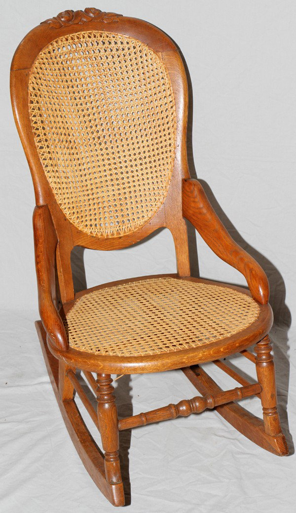 LADIES' ANTIQUE OAK ROCKER, H 33", W 19": LADIES' ANTIQUE OAK ROCKER, H 33", W 19":violin form seat back frame with carved rose design at the crest; cane seat and back, contoured arm rests, spindle legs and stretchers ending at the rockers;