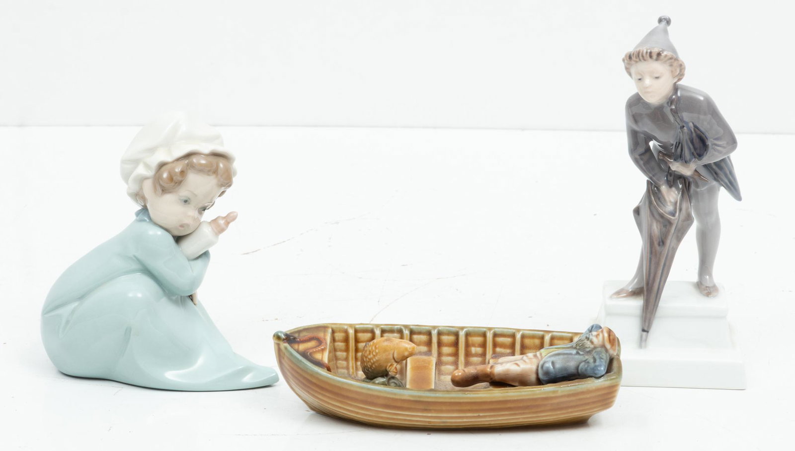 Royal Copenhagen Boy W/ Umbrella, Wade Fisherman & Lladro Porcelain Figures H 7'' L 6'' 3 pcs: Royal Copenhagen Boy W/ Umbrella, Wade Fisherman & Lladro Porcelain Figures H 7'' L 6'' 3 pcs | Danish Royal Copenhagen The Sandman Boy with Umbrella Figurine Hand painted. #1129, H 6". Lladro baby wi