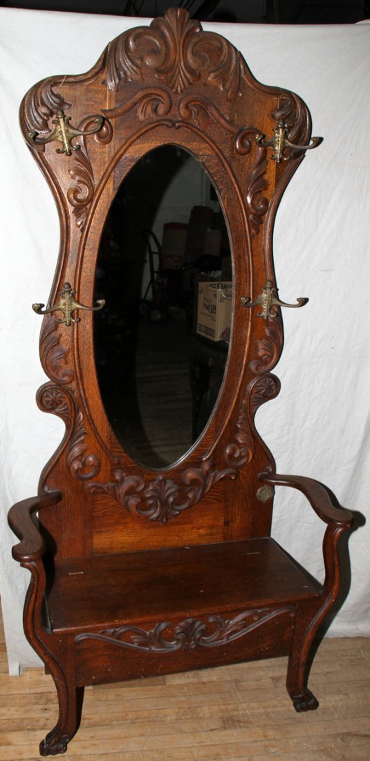 AMERICAN OAK HALL SEAT LATE 19TH C. 84": AMERICAN OAK HALL SEAT, LATE 19TH C., H 84", W 40", D 16 1/2":The shaped back is centered by an oval mirror with acanthus scrolls about and four coat/hat hooks, and a hinged seat flanked by open arms.