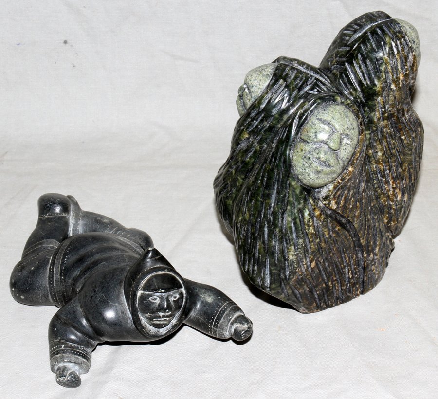 INUIT STONE CARVINGS, TWO, H 2 1/2" & 6": INUIT STONE CARVINGS, TWO, H 2 1/2" & 6":Including 1 figure of a Eskimo crawling on ice hunting, H. 2 1/2", L. 6" and 1 Cape Dorset soapstone faces [three], by Omalluq Oohutsiak, 2001, H. 6", W. 5"