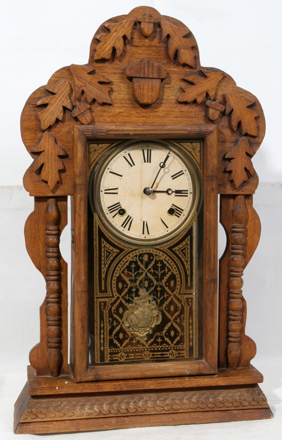 AMERICAN SHELF CLOCK, C. 1890, H 23", W 13": AMERICAN SHELF CLOCK, C. 1890, H 23", W 13":Acorn and oak leaf carved applied decoration. Gilt stencil on door. With key and decorative pendulum.