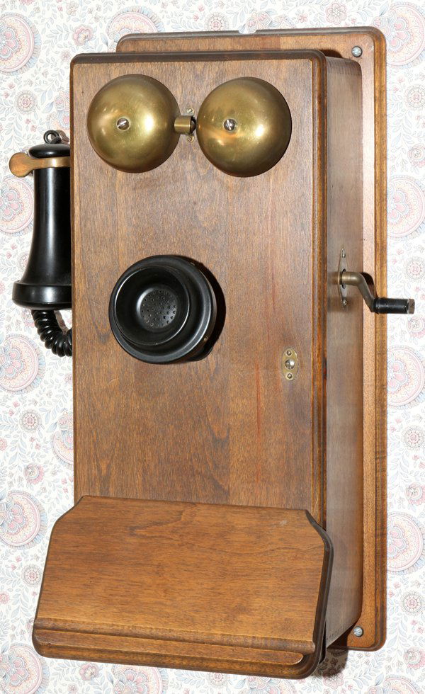 WALNUT CRANK TELEPHONE, H 20": WALNUT CRANK TELEPHONE, H 20", W 9":No apparent markings. With two brass shell bells, black plastic speaker and ear piece. Hand crank ringer on the side