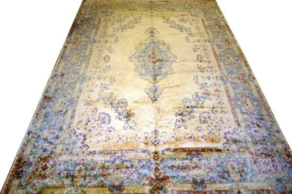 KERMAN PERSIAN WOOL CARPET, 16' 4" X 11' 1": KERMAN PERSIAN WOOL CARPET, 16' 4" X 11' 1":C 1980-1990. Beige open field, center floral medallion along with a floral & leaf design in the borders. From the collection of Joseph & Norina Simon, Gross