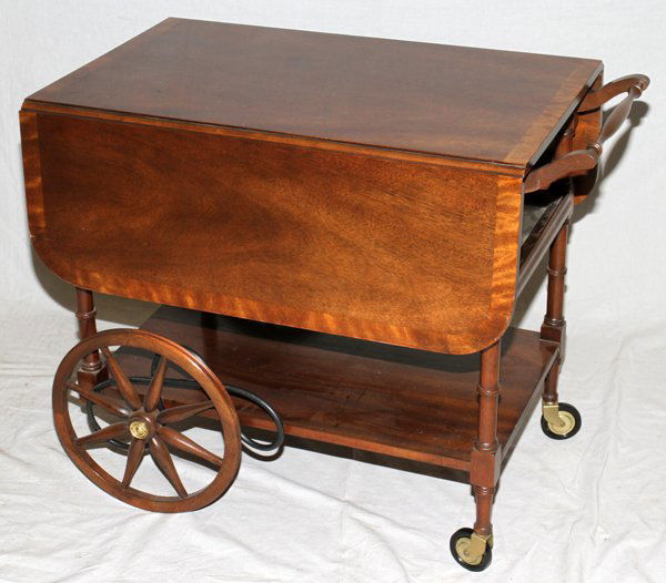 BAKER TEA CART, H 28", L 32", D 19", MAHOGANY: BAKER TEA CART, H 28", L 32", D 19", MAHOGANY:11 1/4" drop leaves. Brown drawer pull, with label in the drawer. Lower stretcher shelf; Accompanied by a glass tray. Large spoked front wood wheels and s
