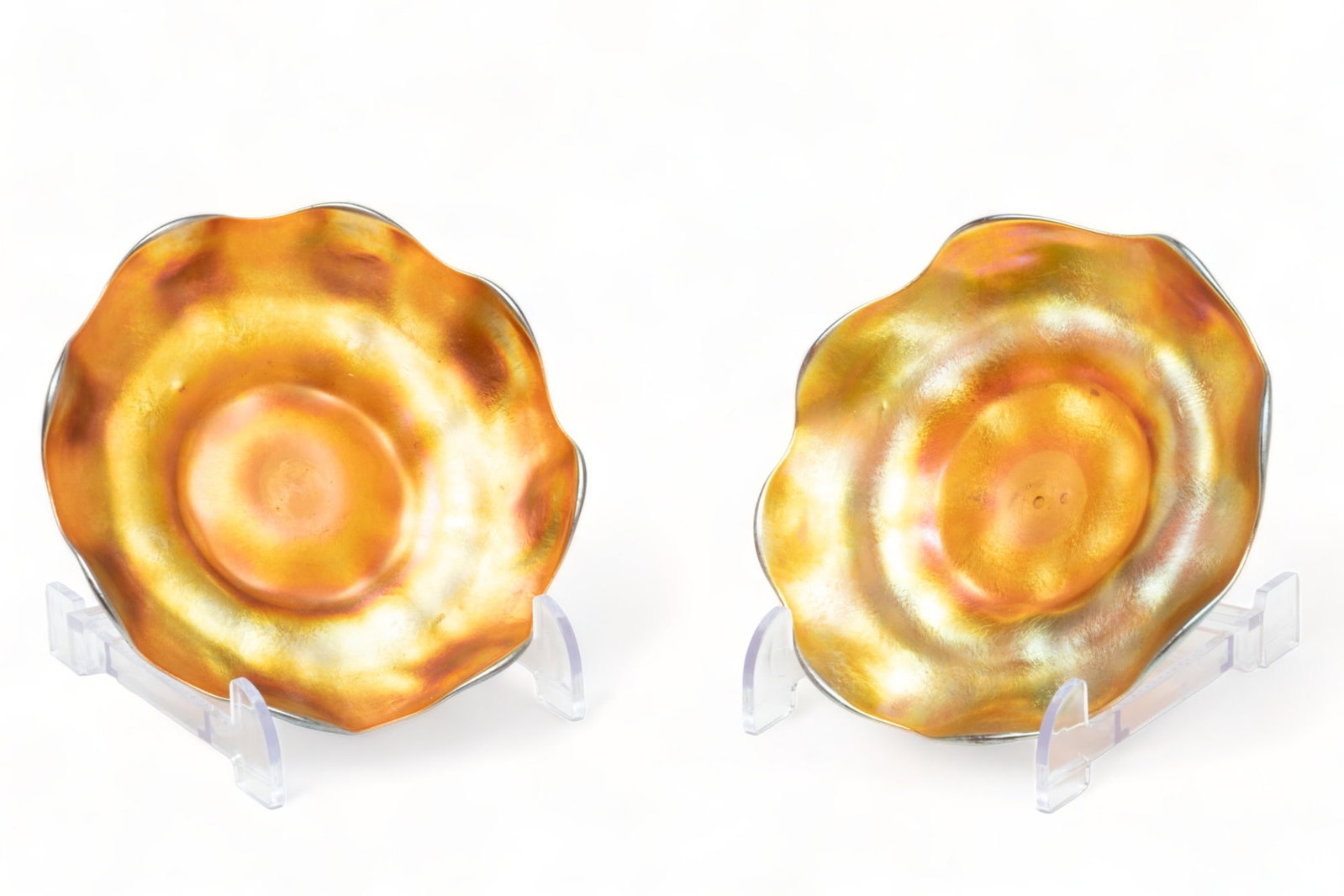Pair of L.C. Tiffany Gold Favrile Underplates H 1" Dia. 6": Pair of L.C. Tiffany Gold Favrile Underplates H 1" Dia. 6" | Unsigned. Gold to purple iridescence. Fluted rims. Provenance: From the Collection of Bethany Belanger, Port Huron, MI.
