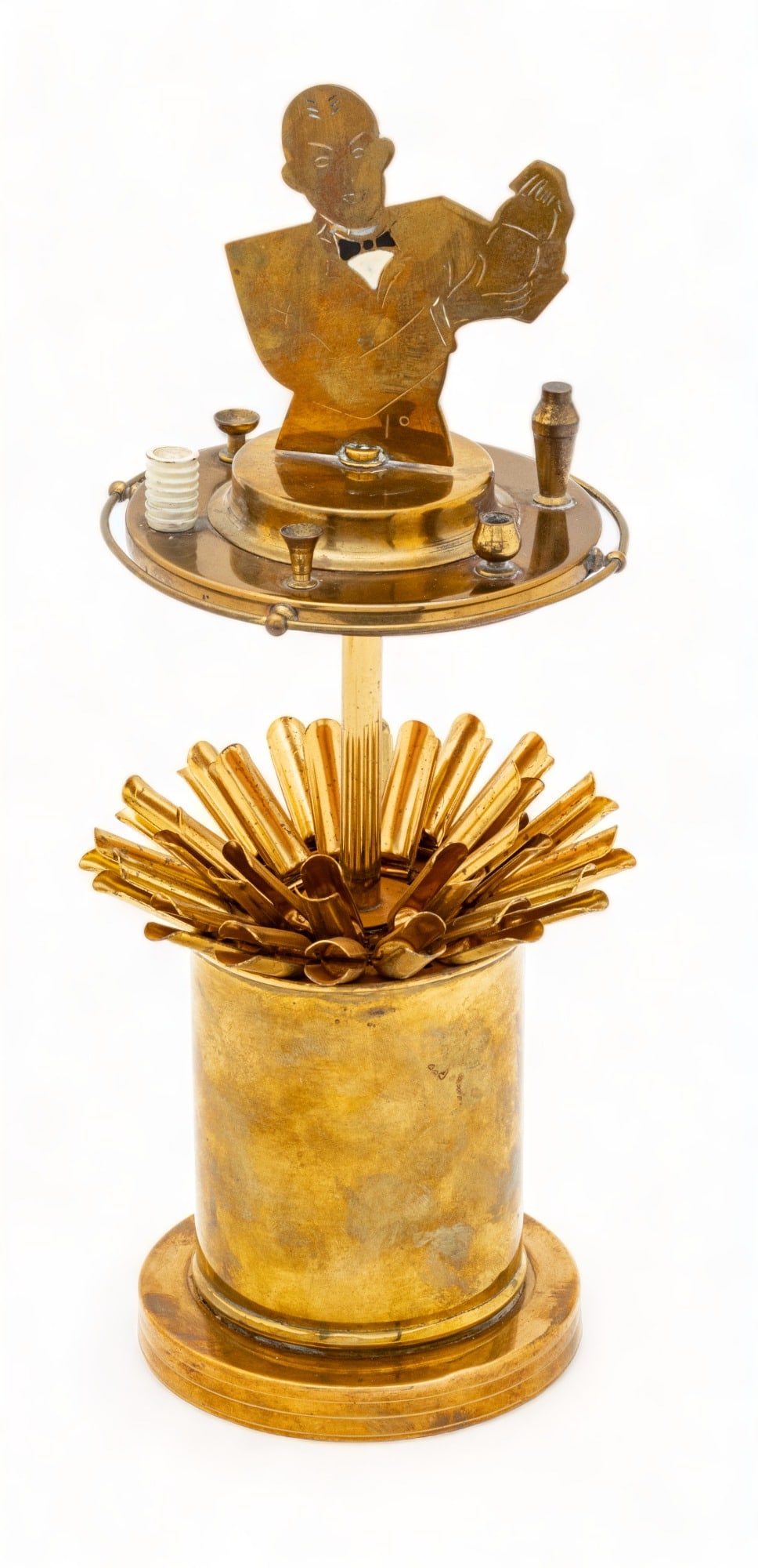 American Brass Bar Top Cigarette Dispenser Ca. 1930, H 8" Dia. 4.5": American Brass Bar Top Cigarette Dispenser Ca. 1930, H 8" Dia. 4.5" | Depicting a bartender in silhouette atop a circular bar with barware. Lifts to reveal a fan of 20 cigarettes. Provenance: From the
