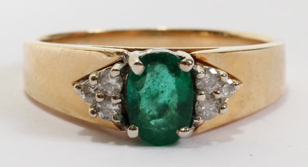 14KT GOLD, EMERALD & DIAMOND RING: 14KT GOLD, EMERALD & DIAMOND RING:A 14kt yellow gold mount centered by an oval cut emerald flanked by three diamonds at either side; stamped "14K EV". Weighs approximately 4.0 grams total.