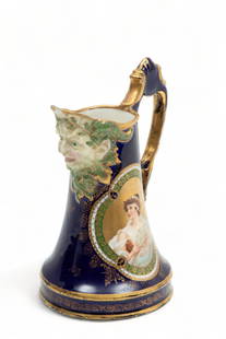 Royal Vienna Porcelain (Austrian) Pitcher Ca. 1920-1930, H 6.5" Dia. 3.5": Royal Vienna Porcelain (Austrian) Pitcher Ca. 1920-1930, H 6.5" Dia. 3.5" | Royal blue ground with fired gold accents. Satyr mask semi-relief spout. Fired gold ground cartouche of woman singing to she