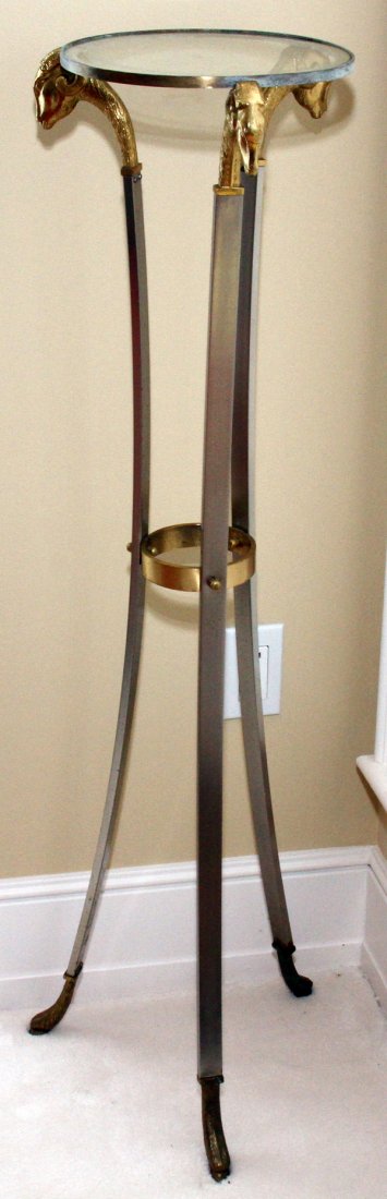PATINATED METAL PLANT STAND, H 44", DIA 10": FRENCH EMPIRE STYLE PATINATED METAL PLANT STAND, H 44", DIA 10":Circular glass top on three ram's head supports ending in hoof feet; white metal with gilt accents.