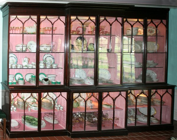 GEORGIAN MAHOGANY BREAKFRONT, IN THREE PARTS: GEORGIAN MAHOGANY BREAKFRONT, IN THREE PARTS, H 97", L 147":Having Gothic influenced panels and a stepped cornice, fitted with 3 plate glass shelves in the upper sections, with watered silk cupboard s