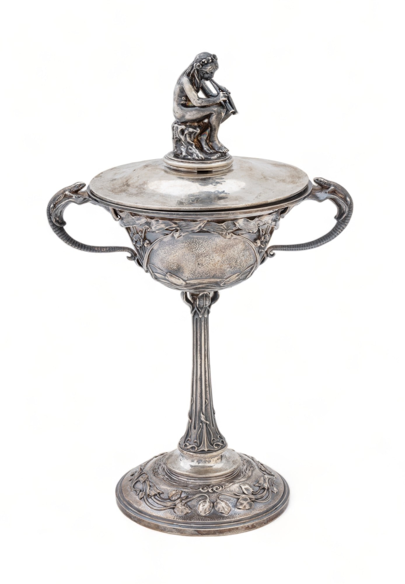 Signed 'E. Sichel' Art Nouveau Silver Plate Covered Tazza, Ca. 1920, H 12" W 6" L 8": Signed 'E. Sichel' Art Nouveau Silver Plate Covered Tazza, Ca. 1920, H 12" W 6" L 8" | with a nude playing an aulos on the cover handle. the bowl has lizard form handles with Art Nouveau floral and te
