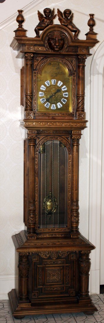 GERMAN STYLE WHITE OAK GRANDFATHER CLOCK 20TH C: GERMAN STYLE WHITE OAK GRANDFATHER CLOCK, 20TH CENTURY, H 101", L 26", D 19":Carved angels on an arched crest above a carved lion's mask with finials above a beveled arched paneled glass door flanked 