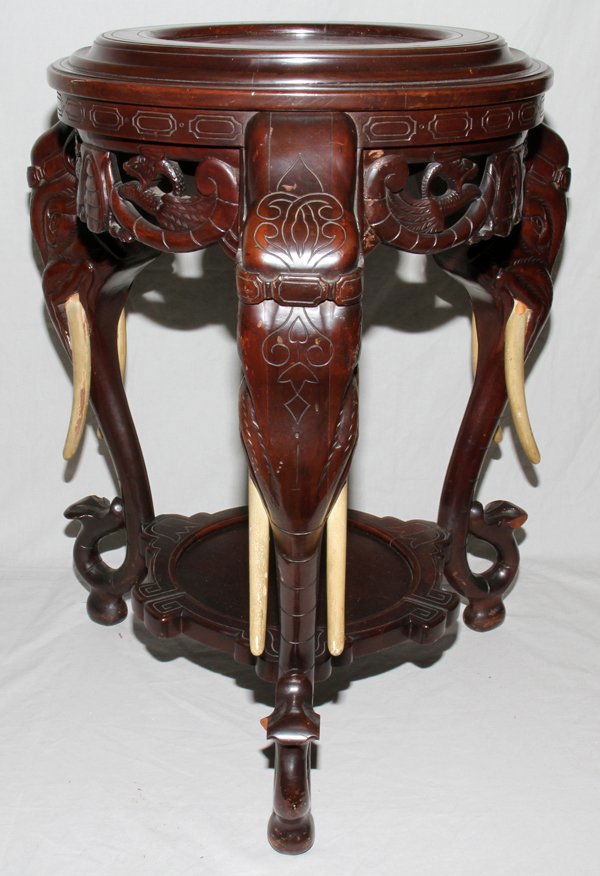 ORIENTAL WOOD ROUND STAND W/ELEPHANT HEAD MOTIF: ORIENTAL CARVED WOOD ROUND STAND WITH ELEPHANT HEAD MOTIF, H 28", DIA 21":having a recessed round top with carved fish in a pierced design skirt below the top; three carved elephant masks with carved
