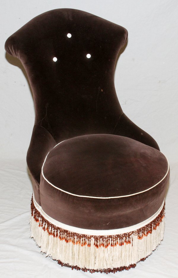 BOUDOIR/SLIPPER CHAIR, H 40": BOUDOIR/SLIPPER CHAIR, H 40":The chair is on wheels and features brown velvet upholstery with beige fringe on the bottom.