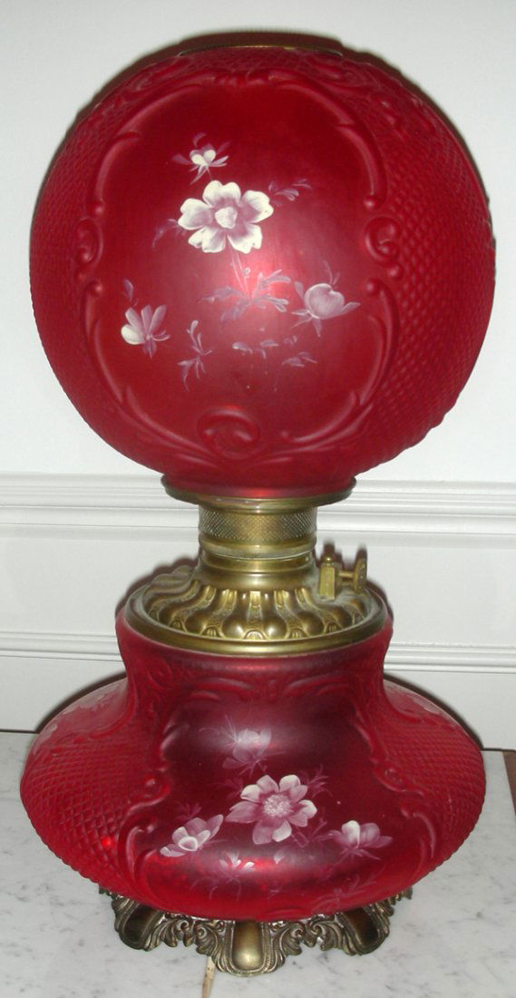 VICTORIAN RED GLASS GONE-WITH-THE-WIND LAMP: VICTORIAN RED GLASS GONE-WITH-THE-WIND LAMP, 19TH C., H 19":Painted white flowers, molded shade. Brass fittings.